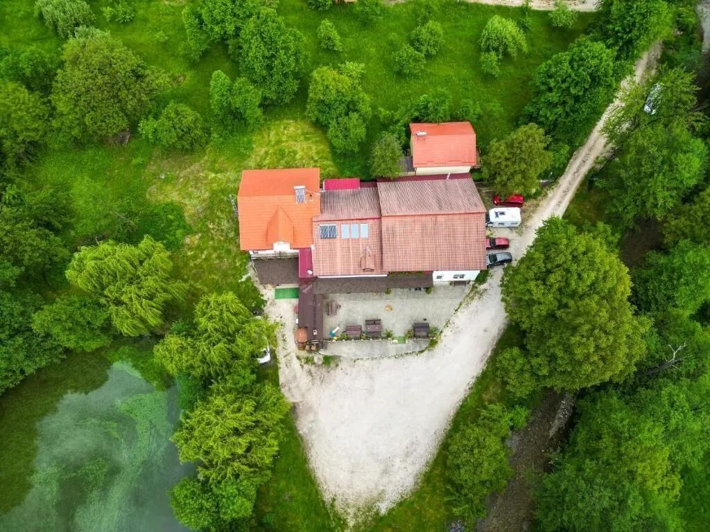 Vedere aeriană a pensiunii, cu curtea și pădurea din jur